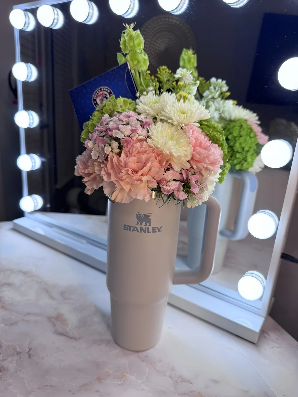 Soft pink and ivory flowers arranged in a neutral tumbler