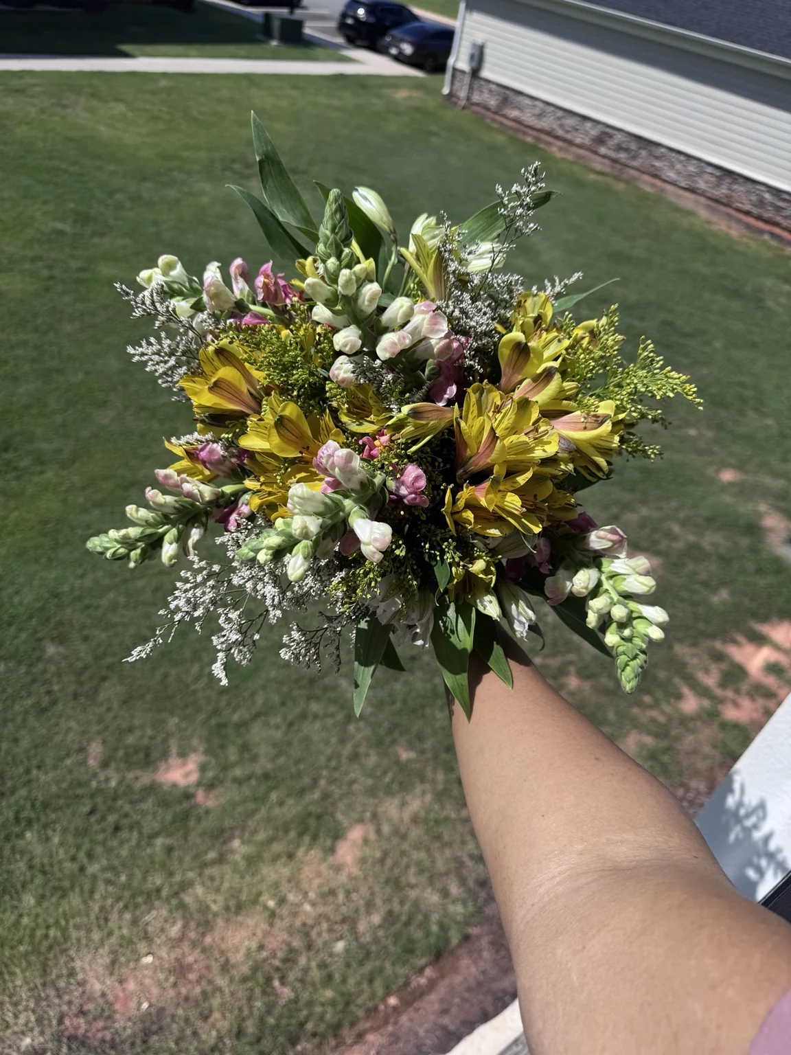Garden-style bouquet of yellow flowers and textured greenery