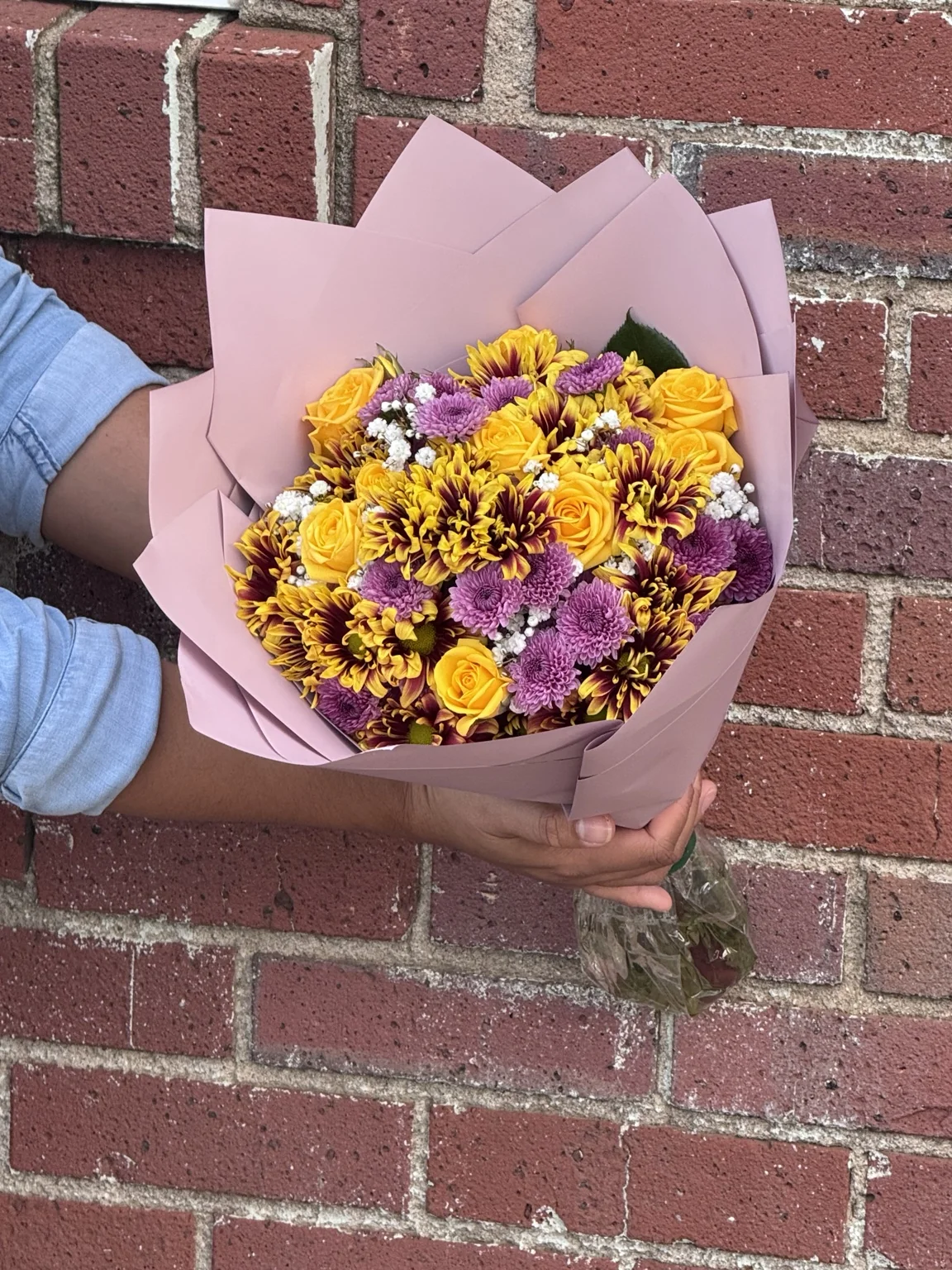 Yellow and purple seasonal bouquet in pink wrapping